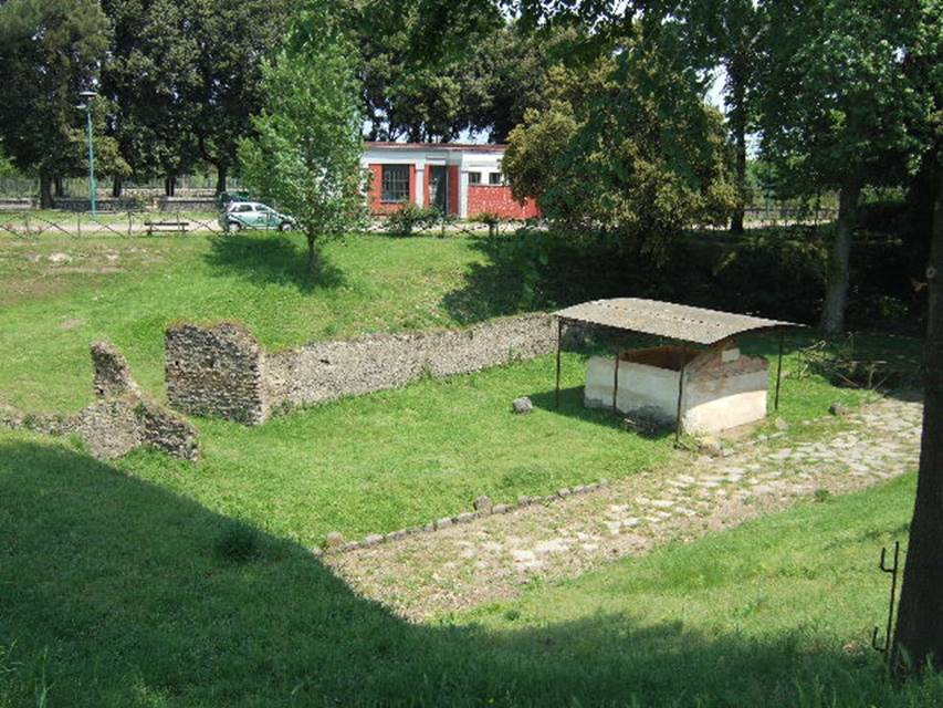 NGOF Pompeii. May 2006. Tomb of M. Obellius Firmus and ancient roadway running past the front.
An ancient wall is to the rear with a gateway in it. In front of this is the area where fifteen bodies were found and casts taken.
See De Caro, S., 1979. Scavi nell'area fuori Porta Nola a Pompei in Cronache Pompeiane V. p. 95-101, figs. 25, 26.